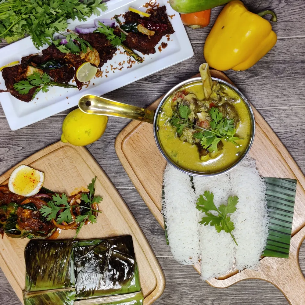 A South Indian spread: grilled meat, curry, string hoppers and herbs on wooden boards
